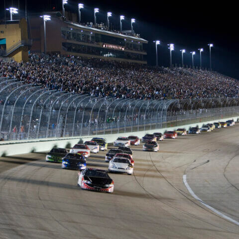 cars racing around a track at night