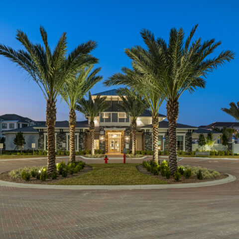 exterior of the Sanctuary at Daytona clubhouse at dusk surrounded by palms and parking